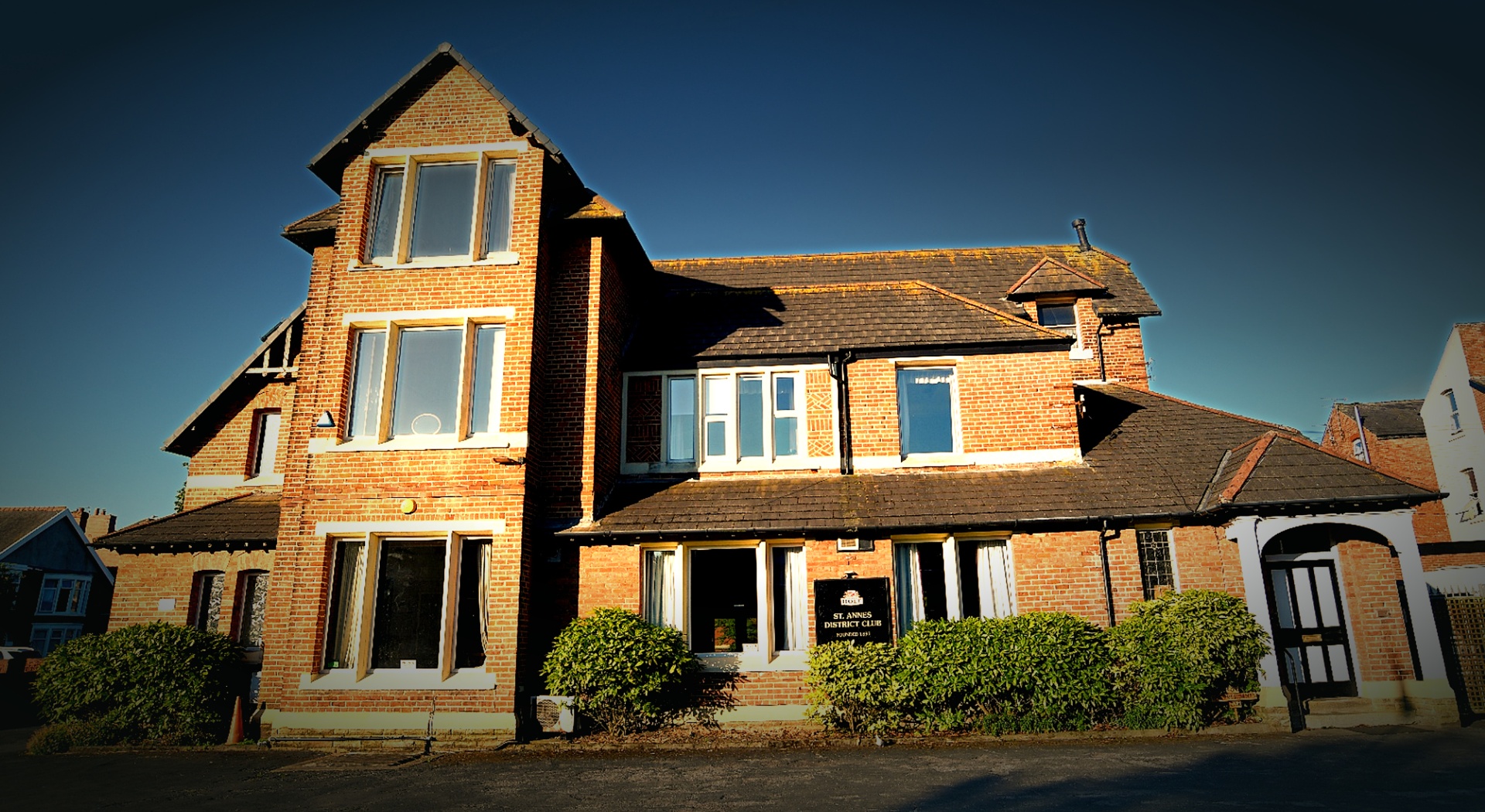 The District Club at golden hour - the brick facade, gable and pillared porch on Clifton Drive South.